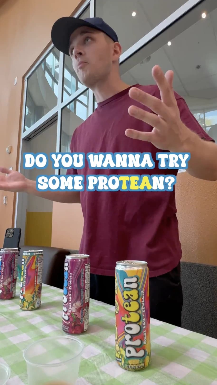 UGC creator presenting canned drinks at a table while talking to camera